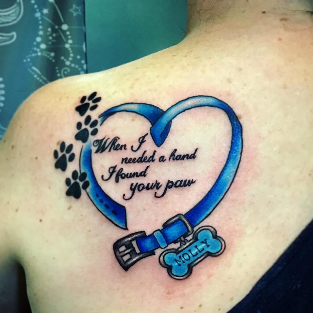 Heartfelt Pet Collar Memorial Tattoo on shoulder with blue leather strap forming heart and bone tag