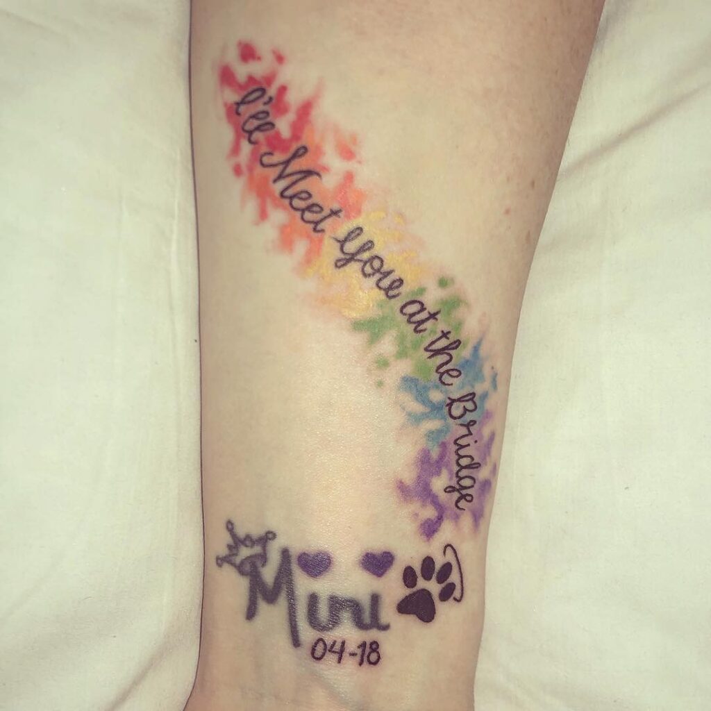 Rainbow Bridge Watercolor Pet Memorial Tattoo on forearm with vibrant rainbow wash and paw print