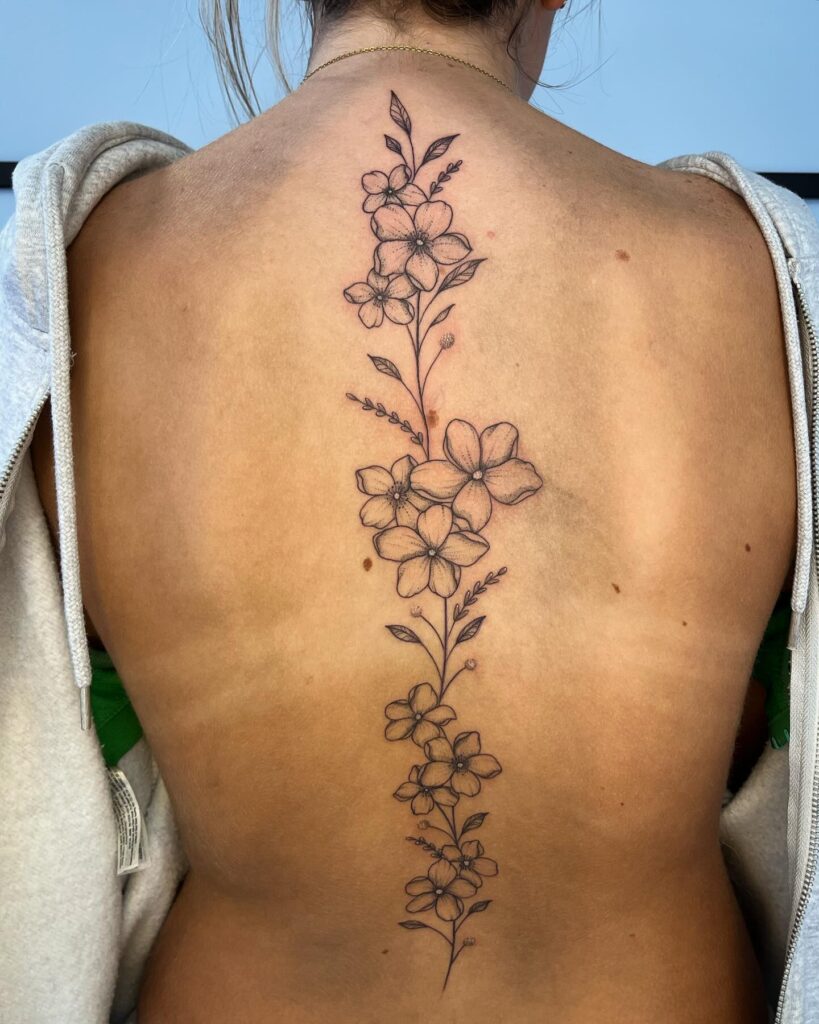 Vibrant Lily And Spanish Quote Spine Tattoo