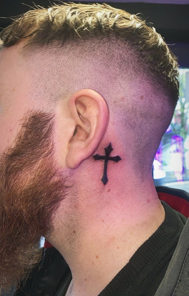 Bold blackwork cross behind the ear