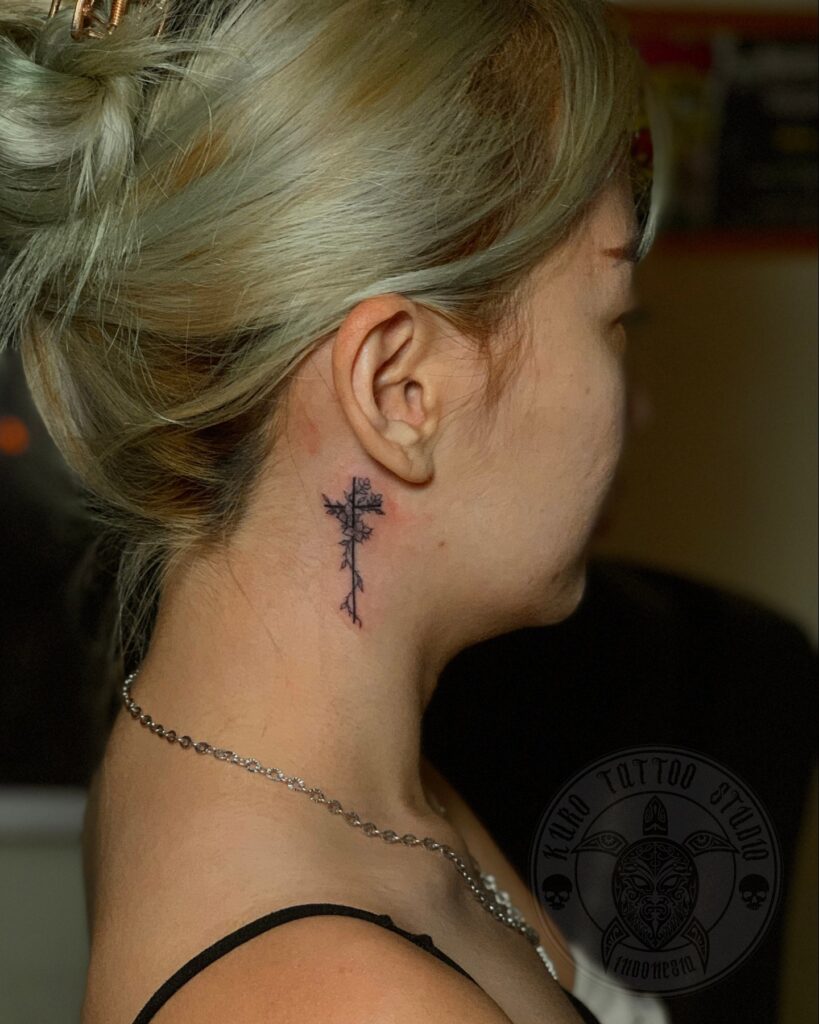 Floral cross behind the ear tattoo