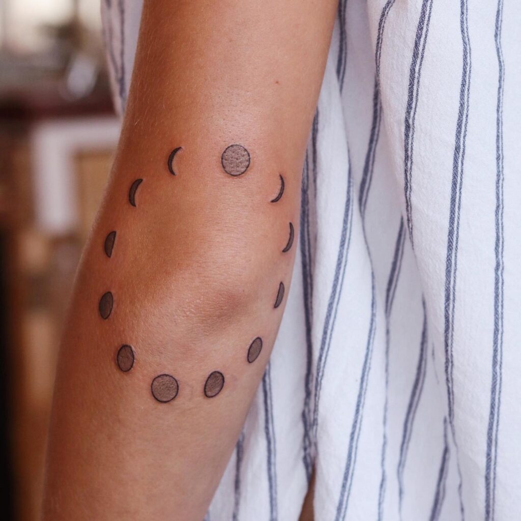 Circular moon phases elbow tattoo