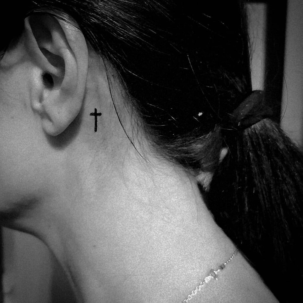 Bold cross behind ear tattoo