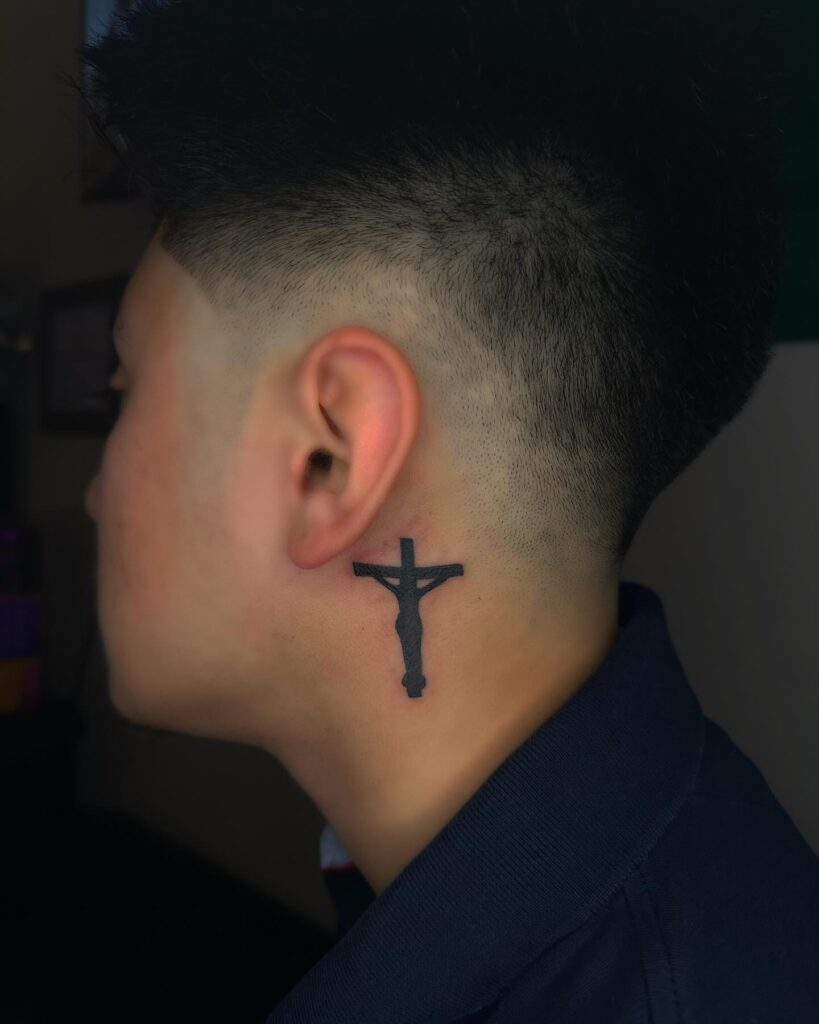 Crucifix silhouette behind the ear tattoo