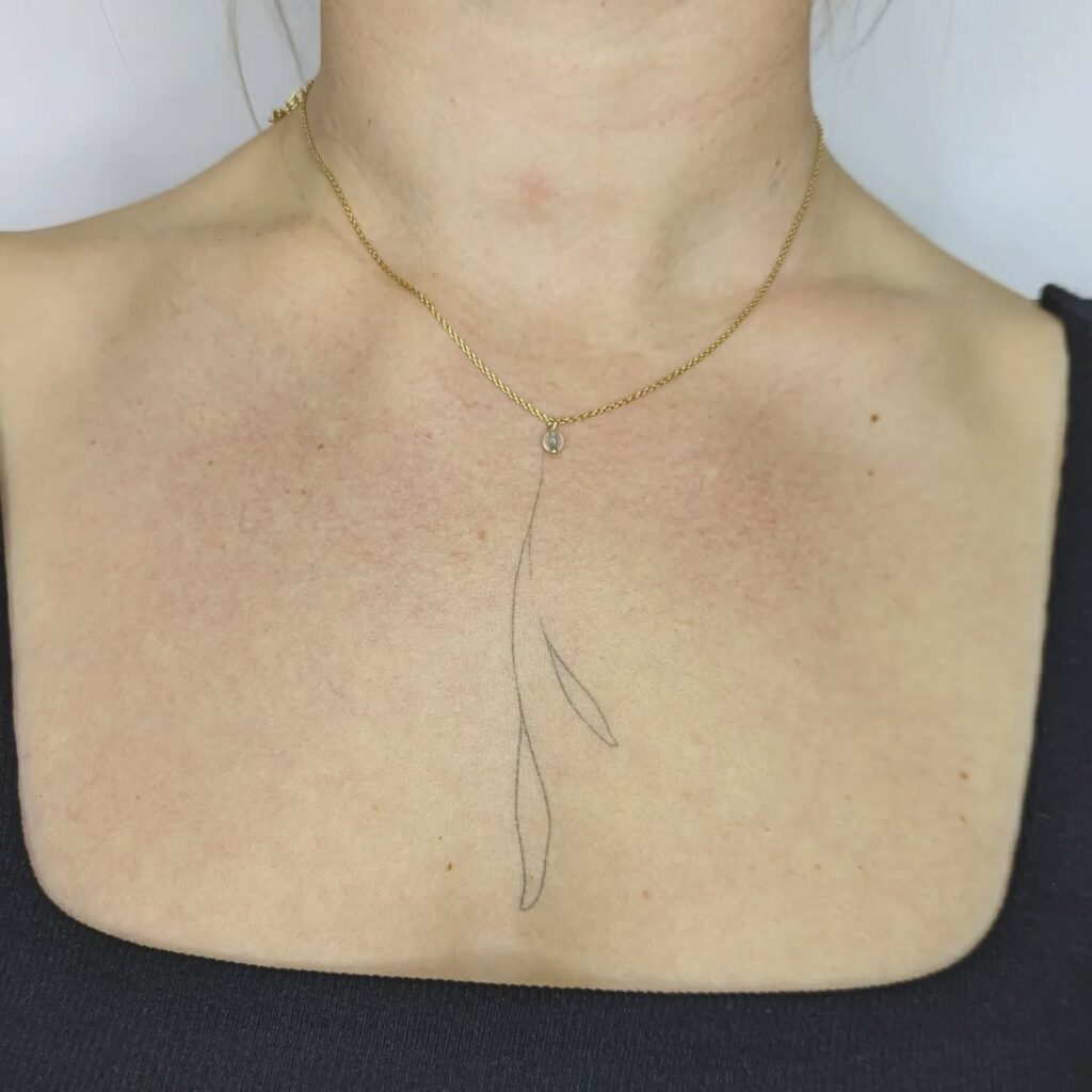Small botanical branch tattoo on the collarbone