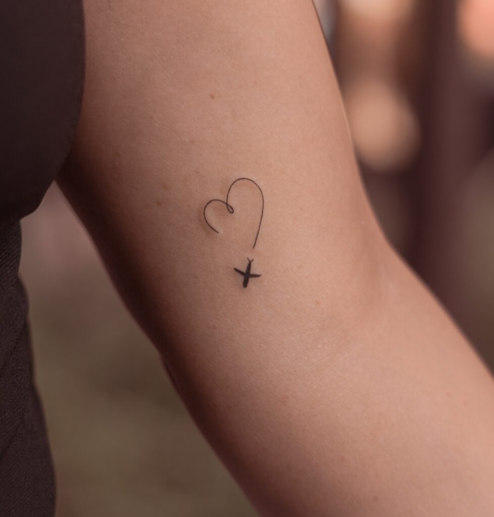 Delicate Paper Airplane and Heart Trail fine line tattoo