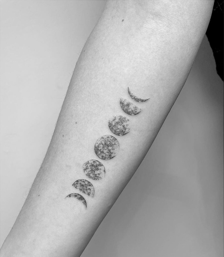 Textured moon phases forearm tattoo with detailed craters