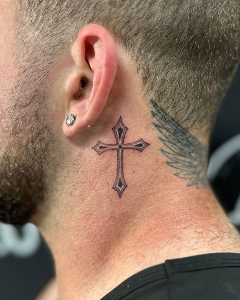 Detailed filigree cross behind the ear tattoo