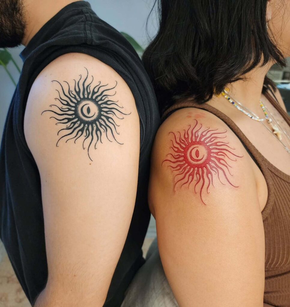 Black and red sun shoulder tattoos with chromatic contrast