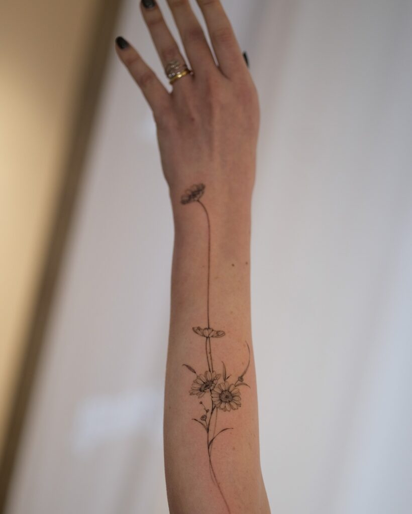 Elegant Daisy Forearm Tattoo with Flowing Design april birth flower tattoo ideas tattoo