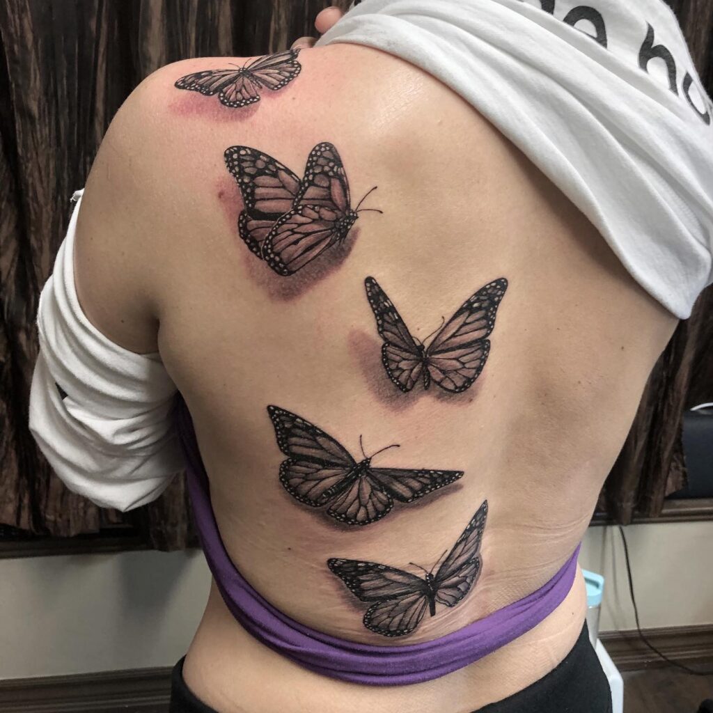 Five monarch butterflies back tattoo