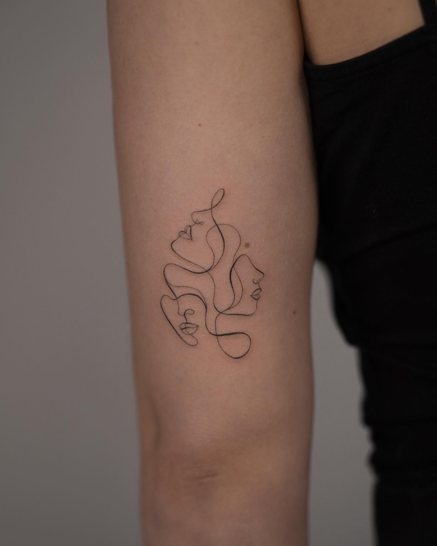 One line female faces tattoo on back
