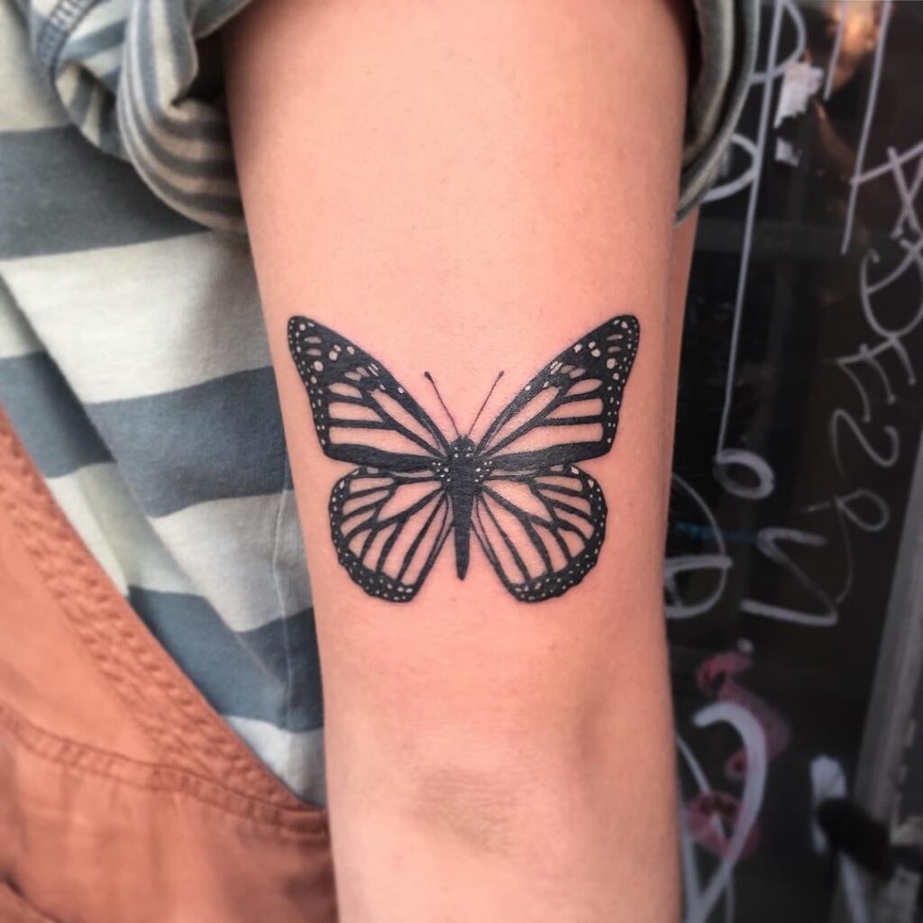 Black ink monarch butterfly tattoo on arm
