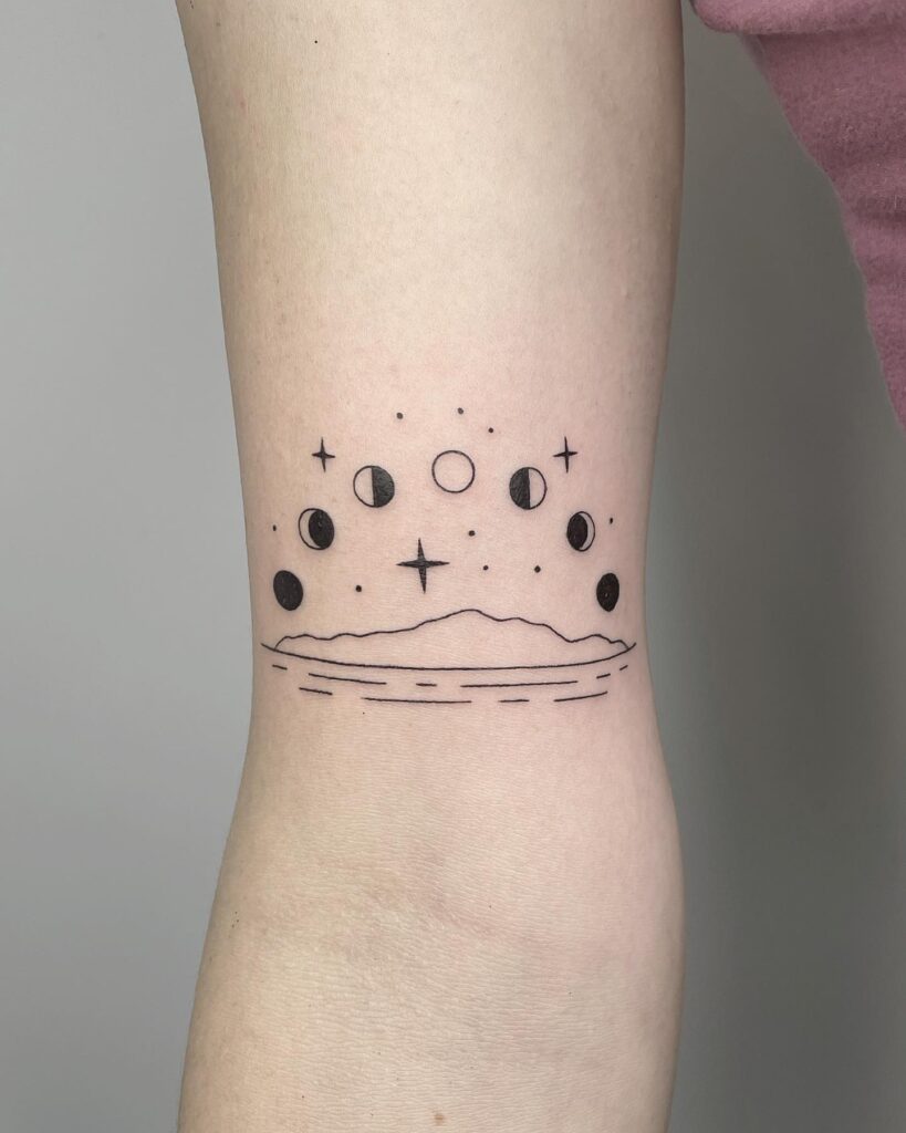 Moon phases above island landscape tattoo