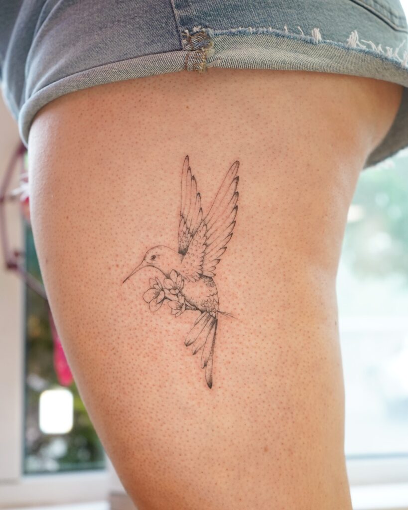 Lightly Detailed Hummingbird with Blossoms on Thigh hummingbird tattoos tattoo