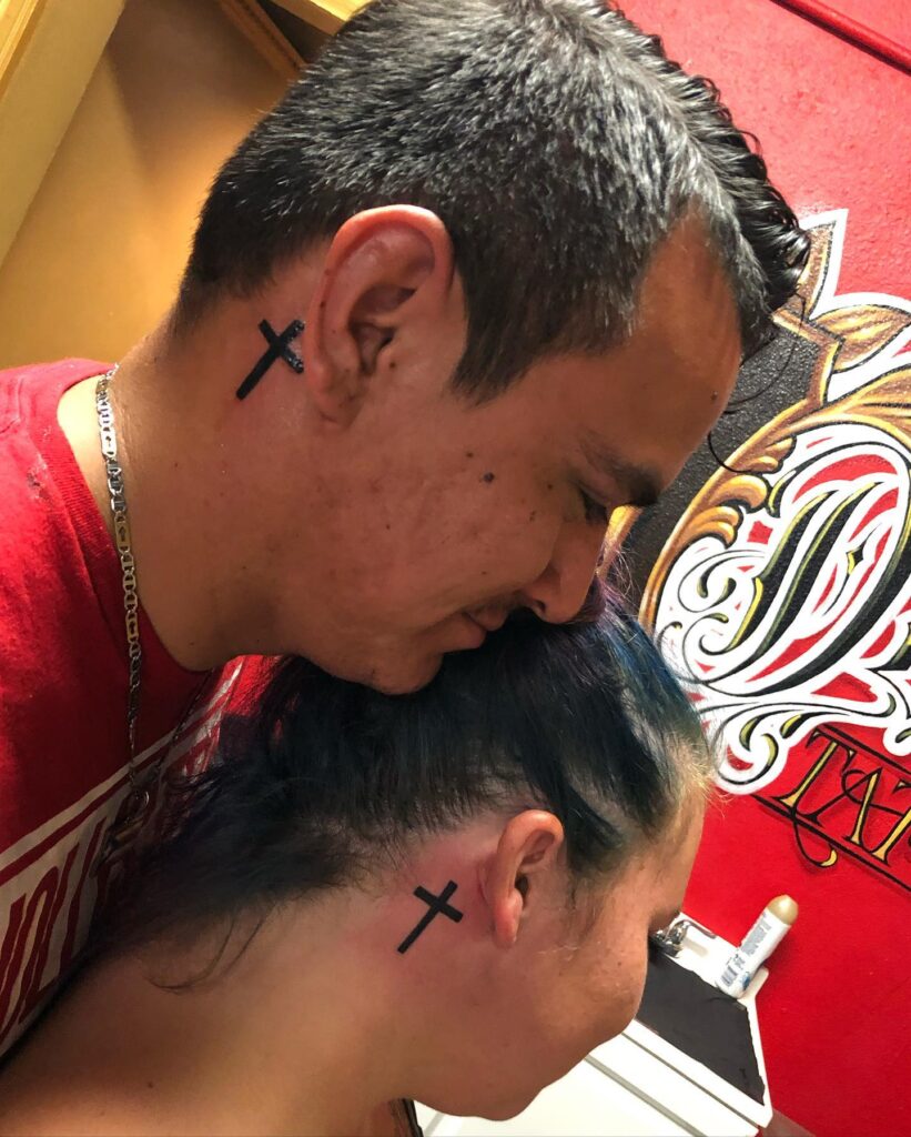 Matching couple cross behind the ear tattoos