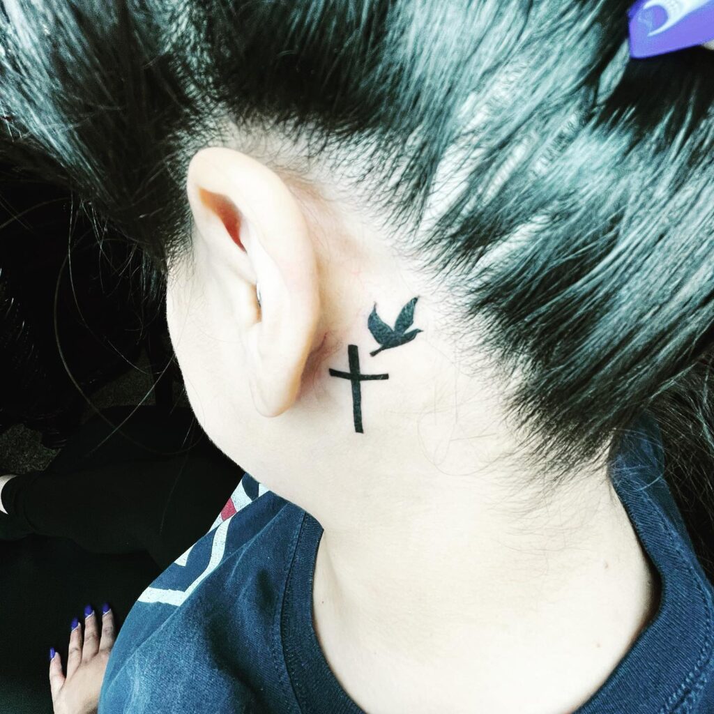 Memorial cross and dove behind the ear