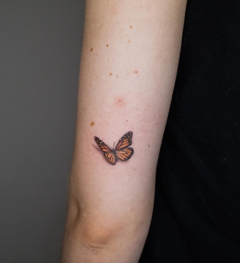 Small monarch butterfly tattoo on upper arm