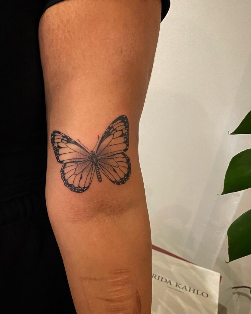 Monarch butterfly tattoo above elbow