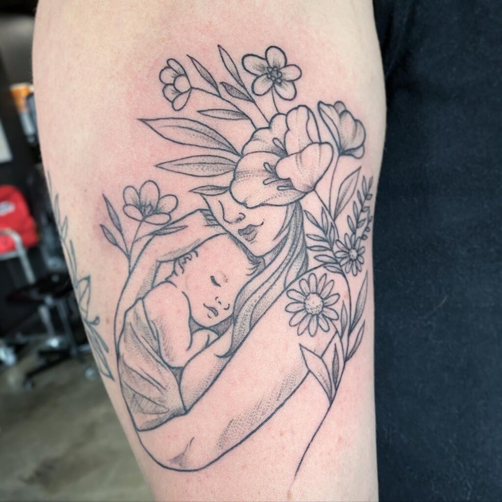 Mother Cradling Baby with Floral Surround Tattoo mommy tattoo ideas tattoo
