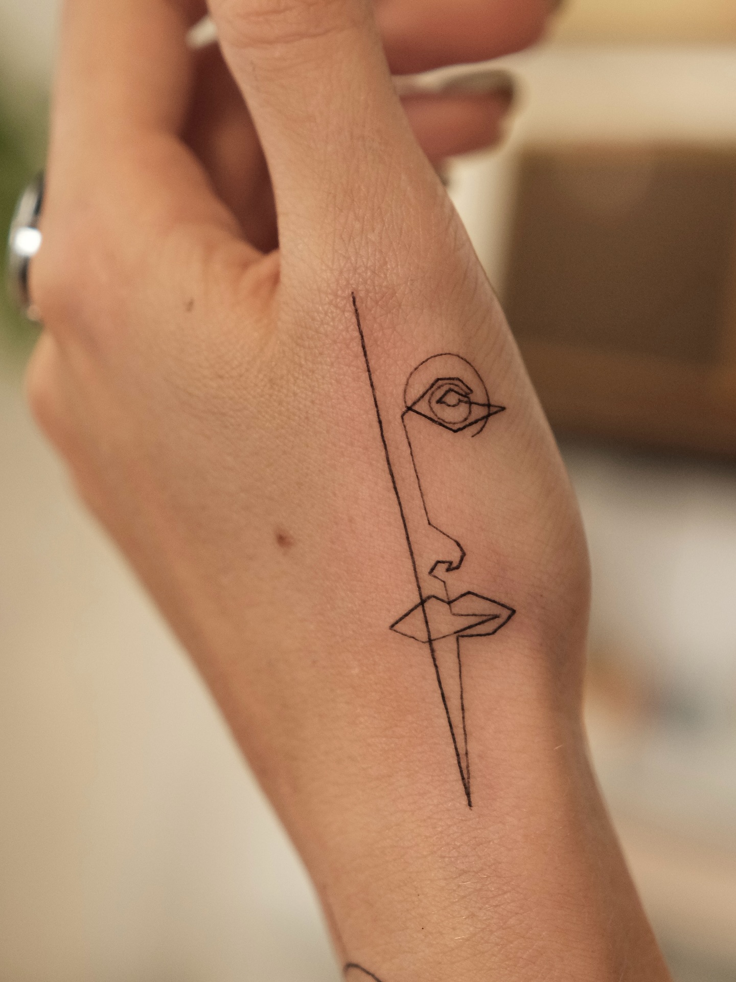 One line abstract face tattoo on upper arm