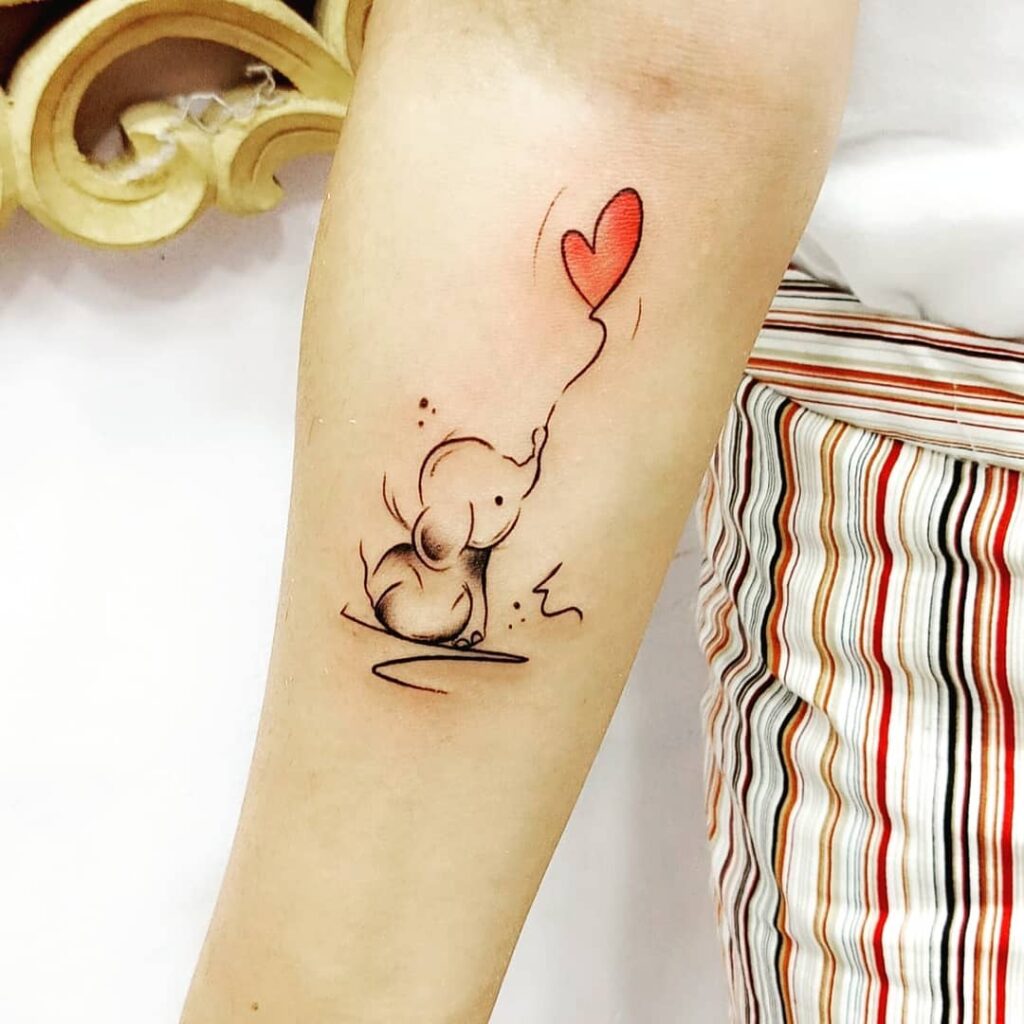 Playful baby elephant tattoo with red balloon