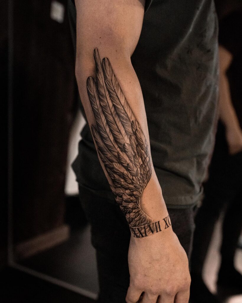 Realistic Angel Wing Forearm Tattoo with Roman Numerals angel wings tattoo ideas tattoo
