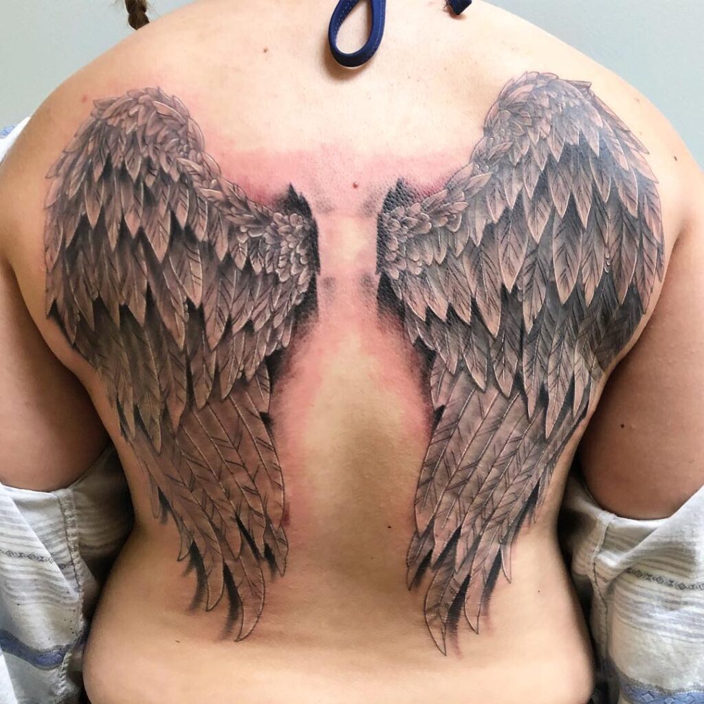 Realistic Full-Back Angel Wings Tattoo with Soft Blush Accent angel wings tattoo ideas on back tattoo