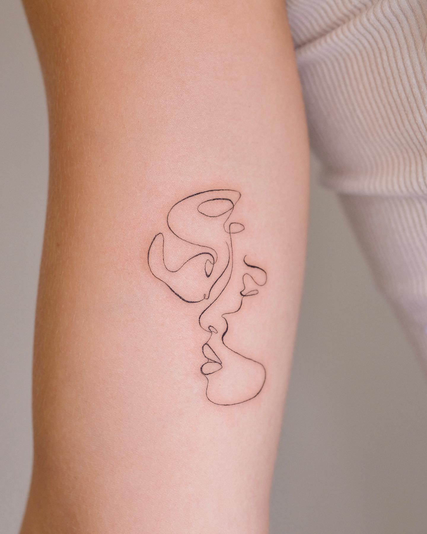 One line couple kiss tattoo on inner arm