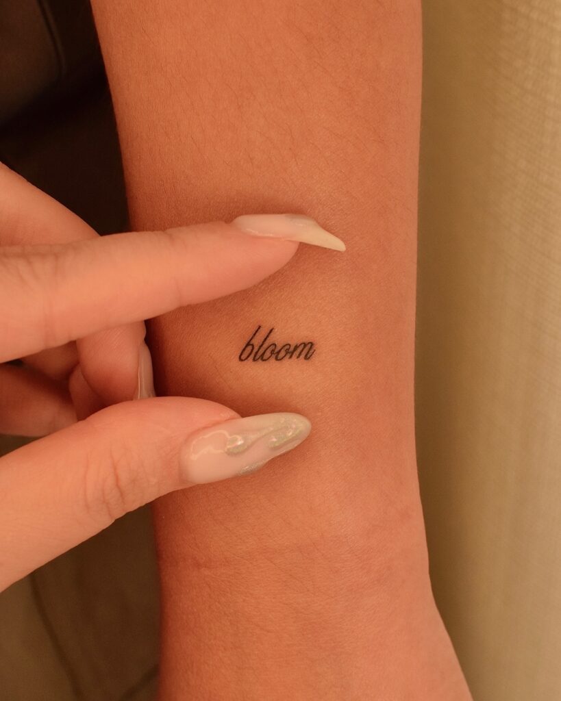Tiny “Bloom” Word Tattoo meaningful tiny tattoos tattoo