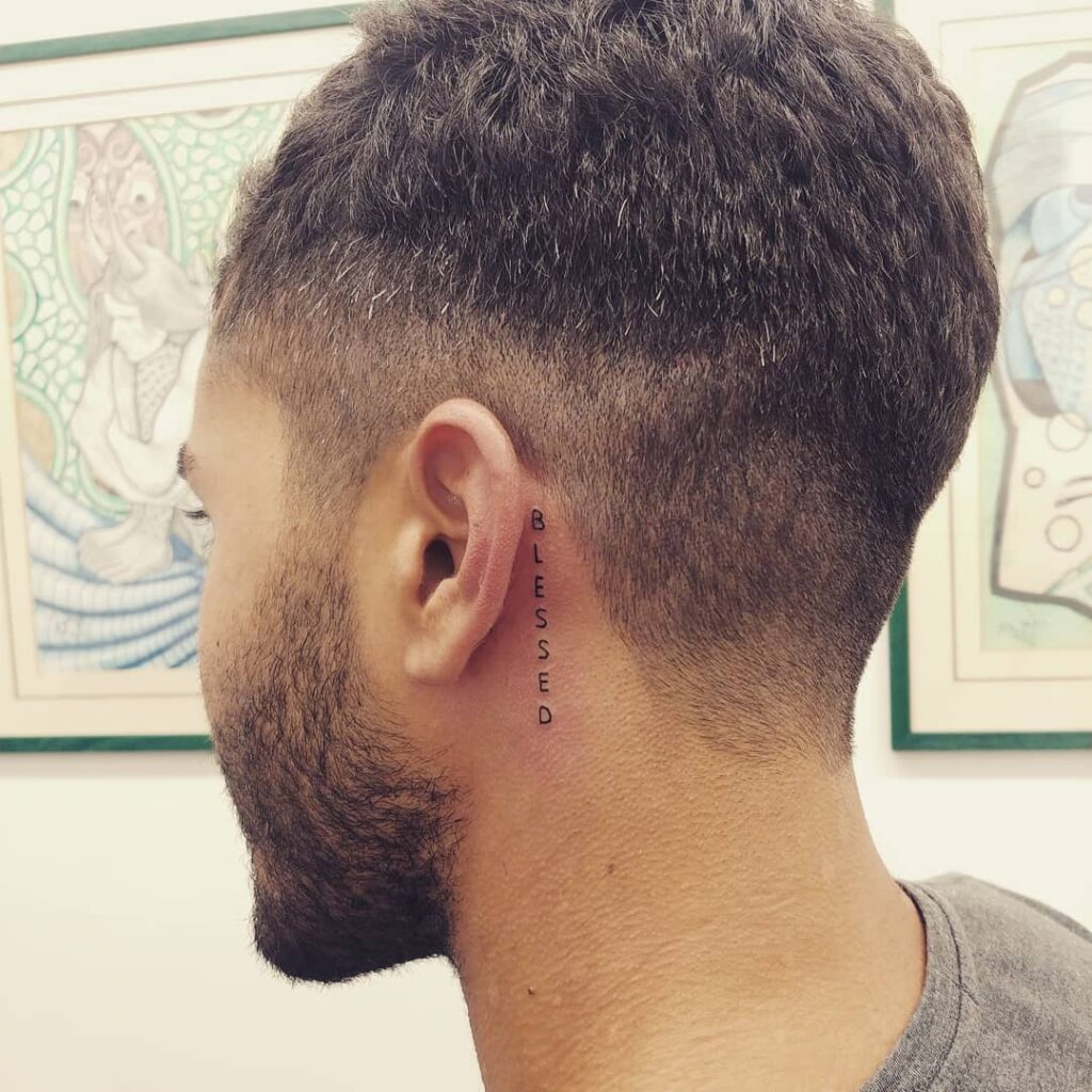 Vertical “Cursed” Lettering Behind the Ear behind the ear tattoo ideas for men tattoo