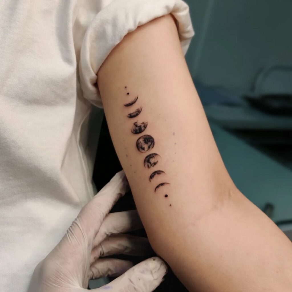 Vertical moon phases tattoo on the outer arm