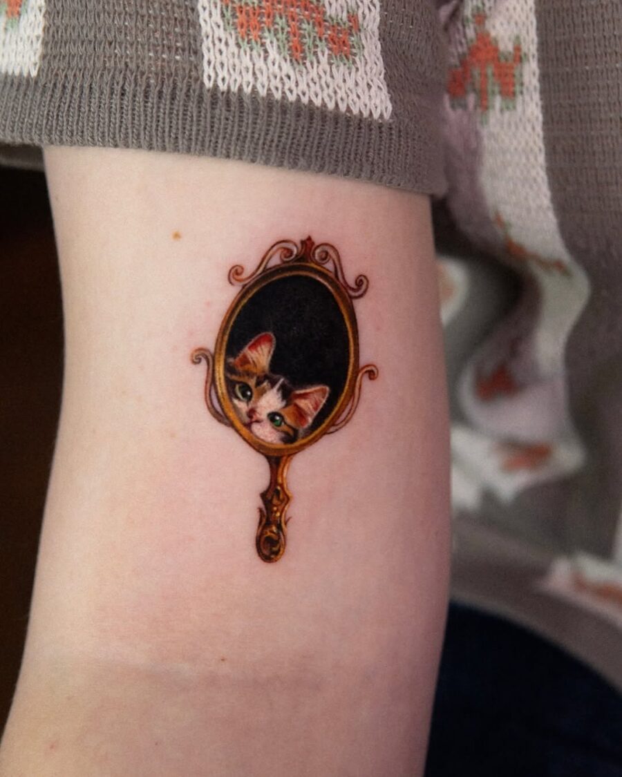 Whimsical cat tattoo framed in vintage style Tattoo on skin