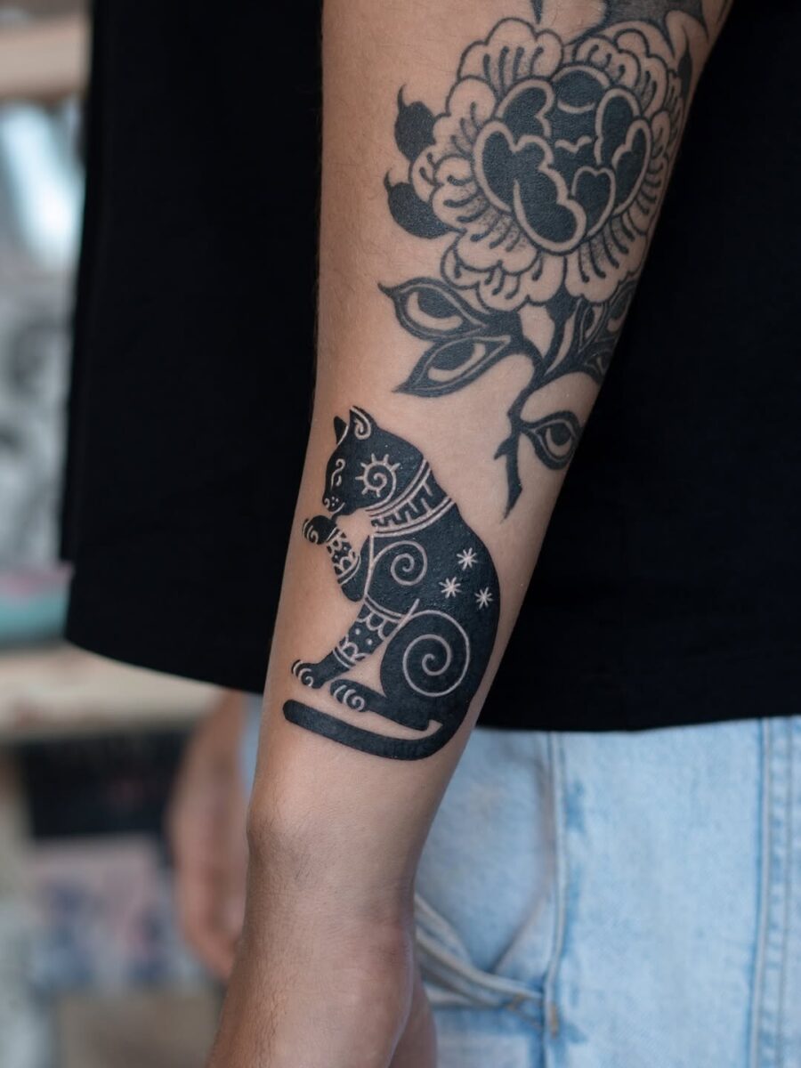 Intricate black cat tattoo with swirling patterns Tattoo on skin