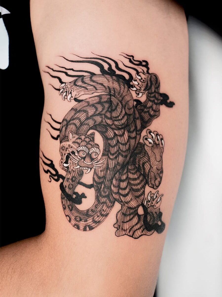 Intricate black ink dragon and tiger tattoo Tattoo on skin