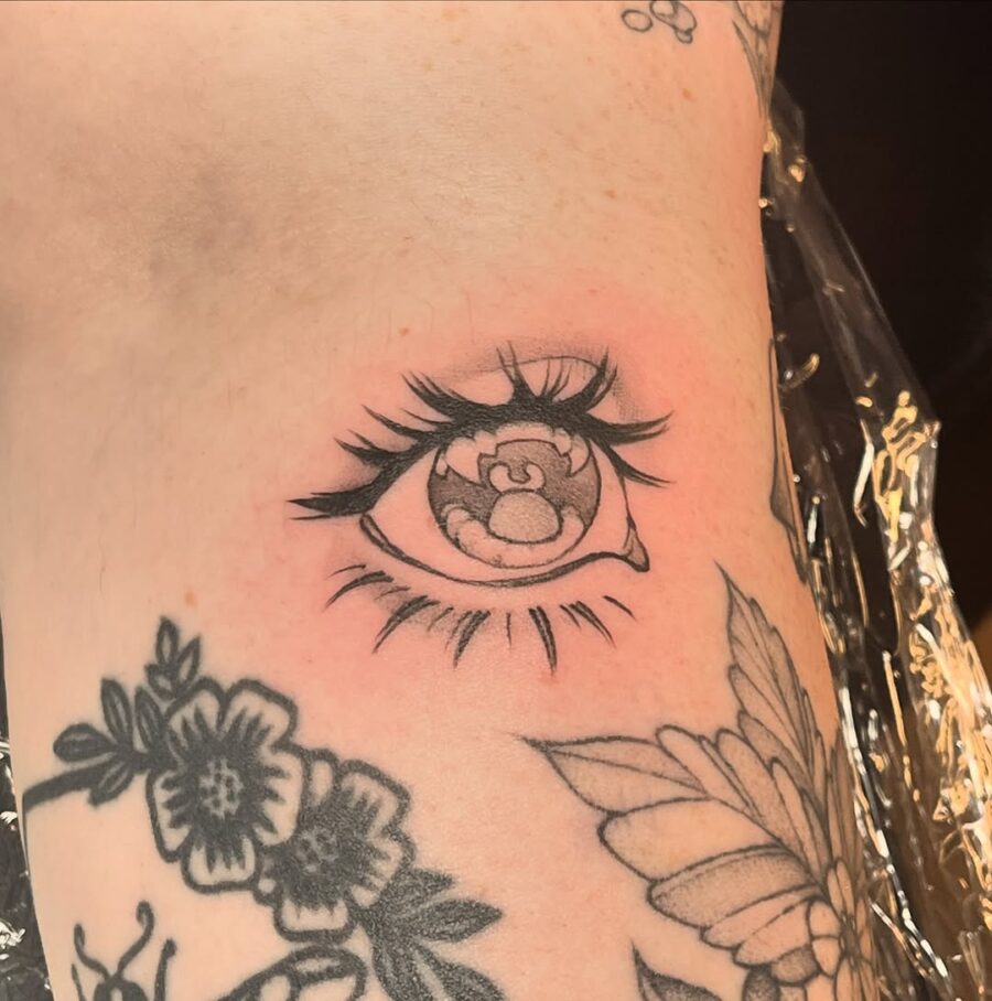 Realistic anime eye tattoo with floral elements Tattoo on skin