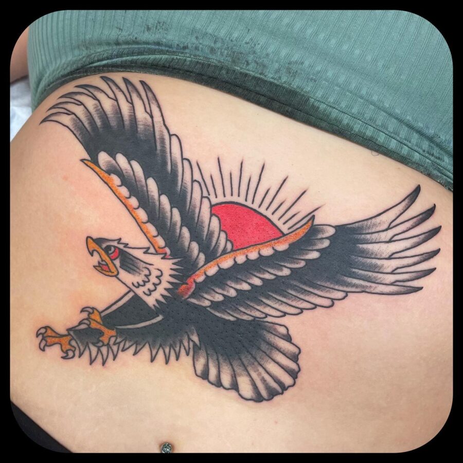 Bold eagle tattoo soaring against vibrant sunset belly tattoos