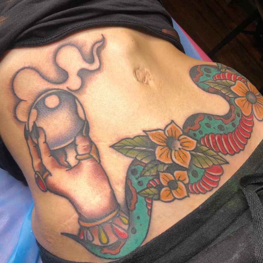 Colorful belly tattoo showcasing hand and snake Tattoo on skin