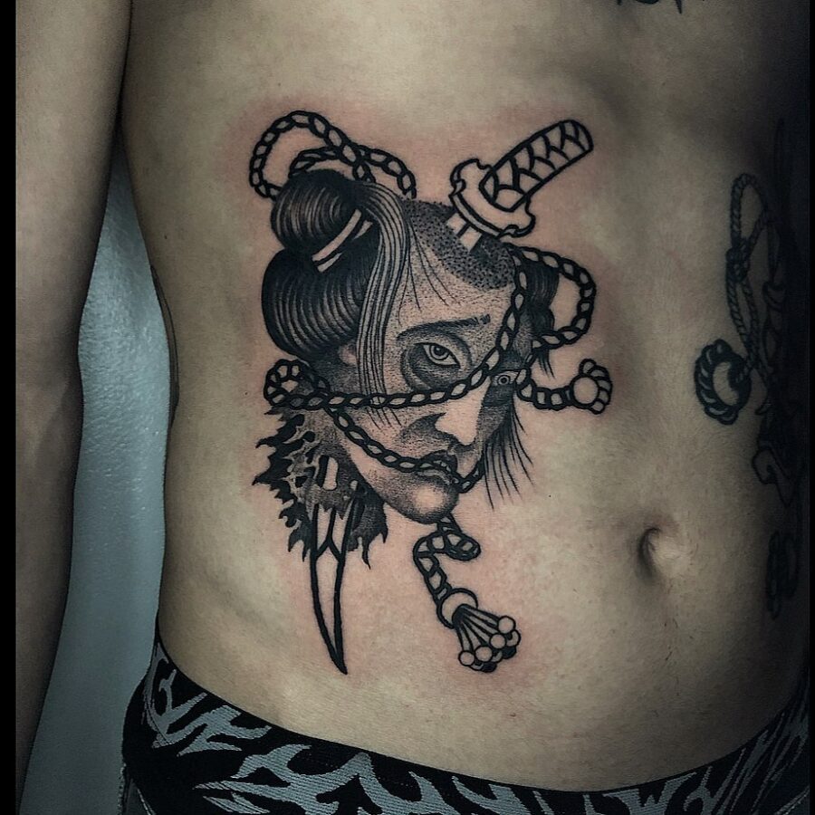 Intricate belly tattoo featuring a woman and blades. Tattoo on skin