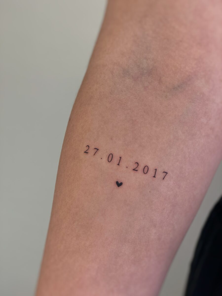 Minimalist birthday date with heart detail Tattoo on skin