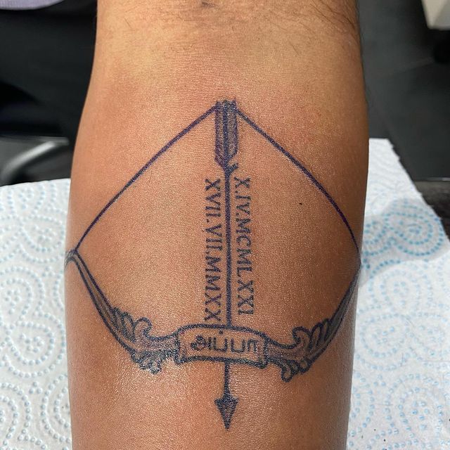 Bow with Roman Numeral Date Dedication Arrow Tattoo Tattoo on skin