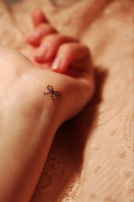 Small bow on wrist Tattoo on skin