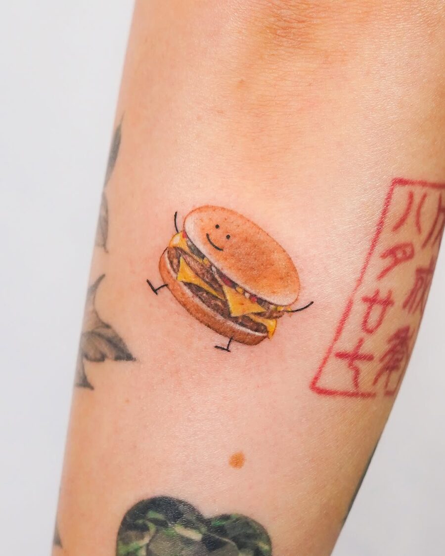 Adorable smiling burger tattoo on an arm Tattoo on skin