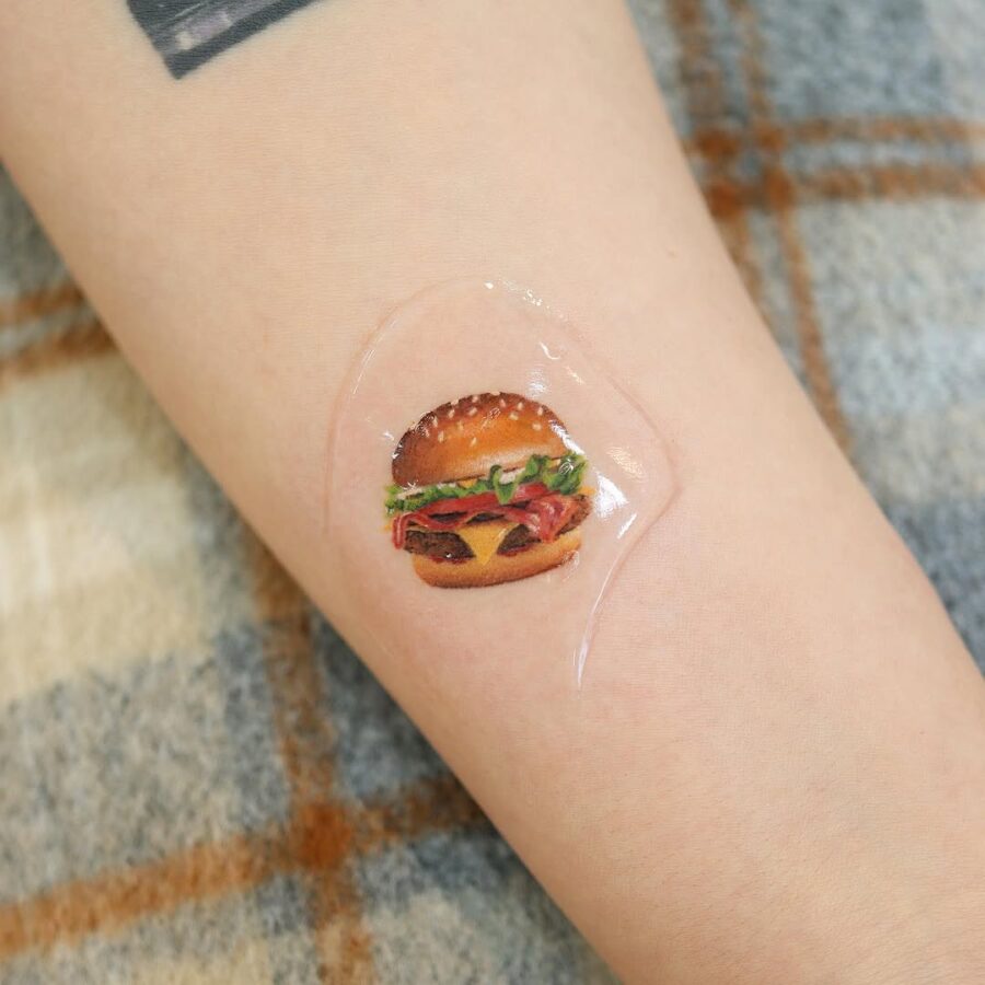 Vibrant hamburger tattoo with playful elements Tattoo on skin