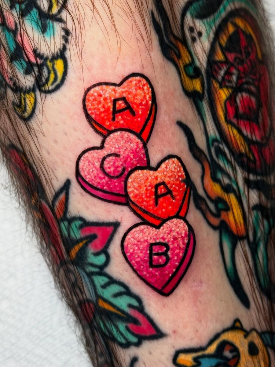 Colorful candy hearts tattoo with playful letters Tattoo on skin
