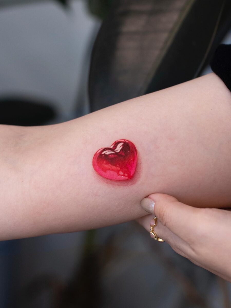 Glossy red heart tattoo on the arm Tattoo on skin