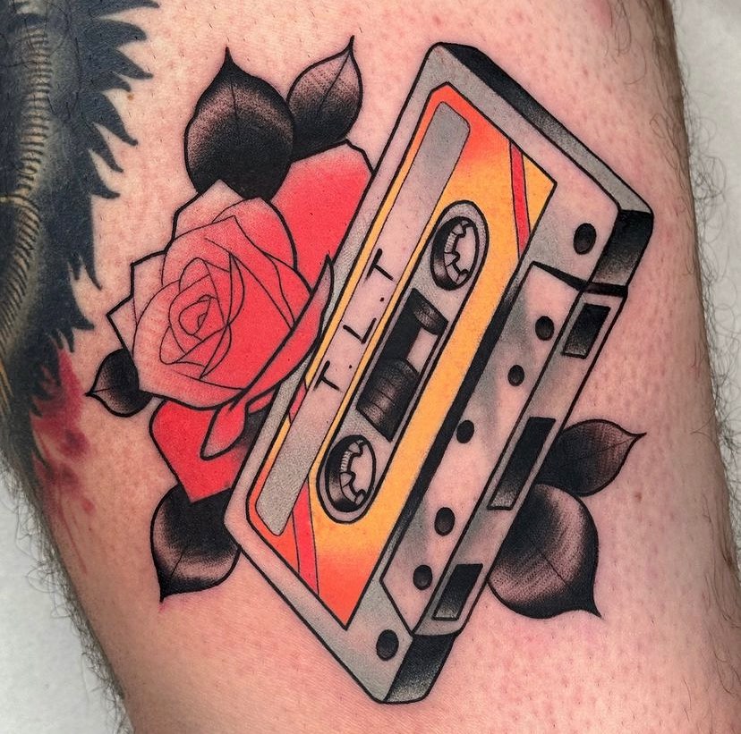 A nostalgic cassette tape amidst bold roses Tattoo on skin