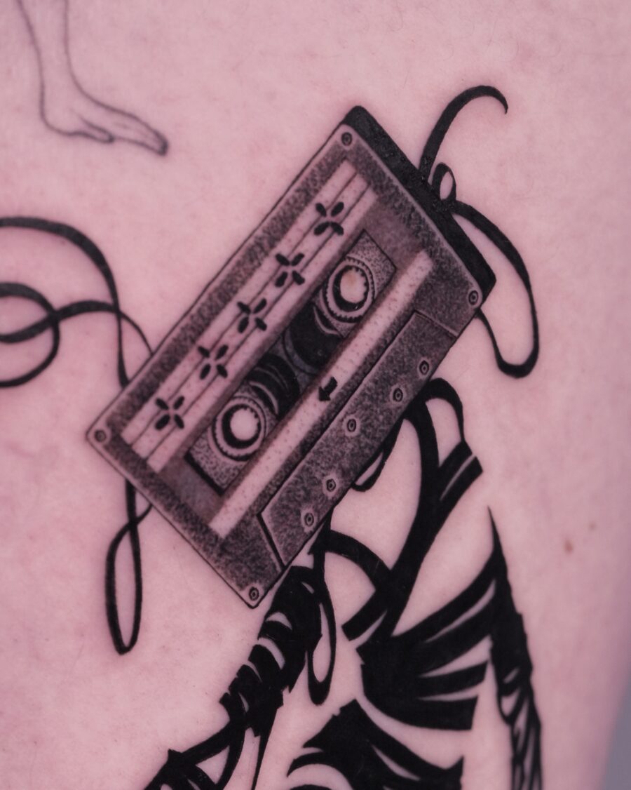 Realistic cassette tattoo with flowing tape details Tattoo on skin