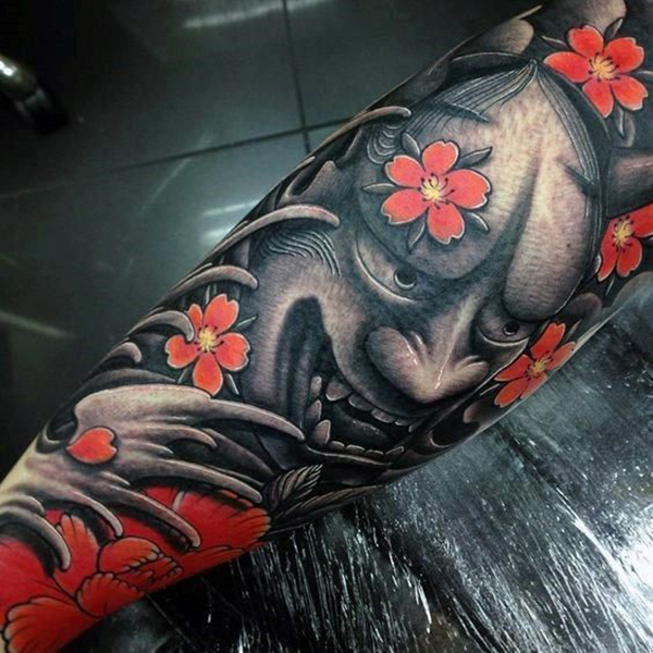The Strange Face Surrounded by Cherry Blossom Flowers Tattoo on skin