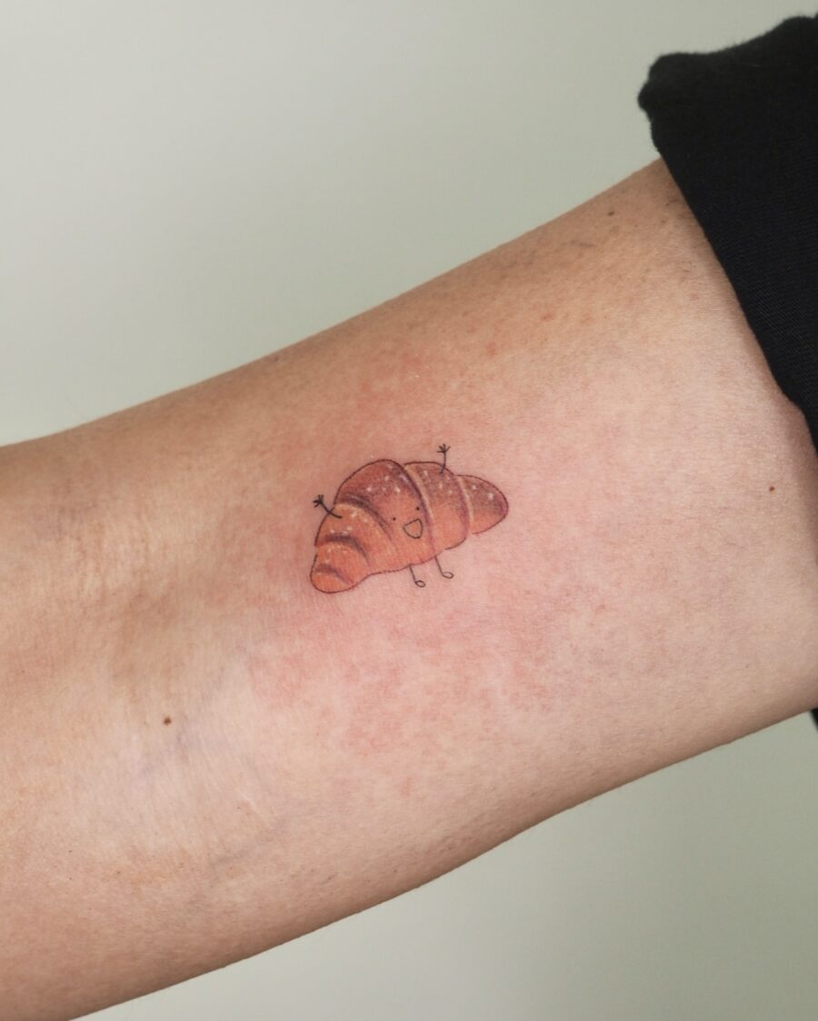 A whimsical croissant tattoo on the forearm Tattoo on skin